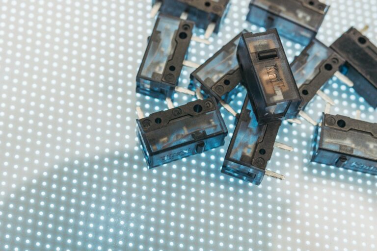 Macro photo of black electronic switches on illuminated LED surface, highlighting technology components.